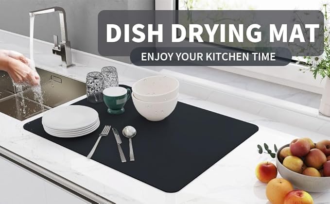 Black kitchen drying mat on countertop with plates, bowls, cups and utensils