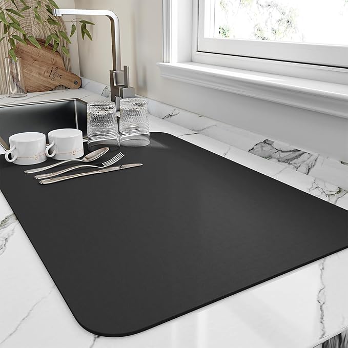 Black quick dry kitchen drying mat on marble countertop beside sink with cups, glasses and cutlery