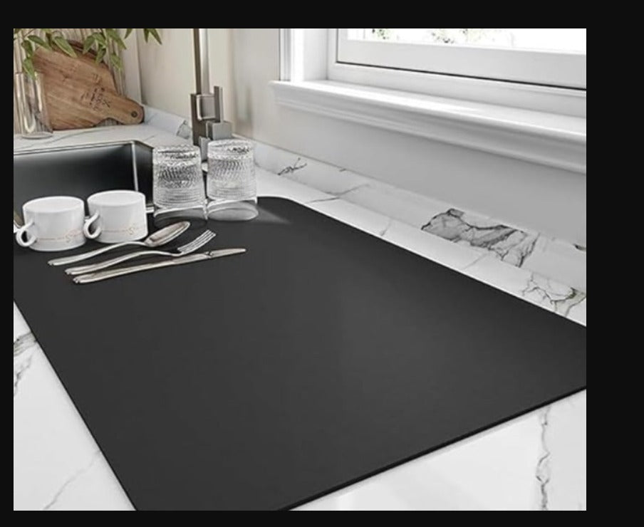 Black kitchen drying mat with rounded corners placed on a marble countertop